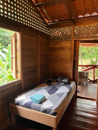 a bed in a wooden room with two windows at Cocles House in Talamanca