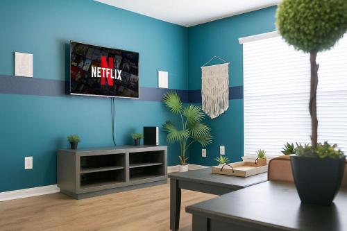 a living room with a tv on a blue wall at Bliss Living with Pool, Gym & BBQ I Lndry in Houston