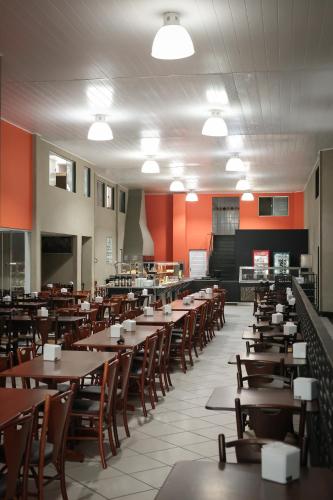 a dining room with tables and chairs and red walls at Hotel QualitySul in Teixeira de Freitas