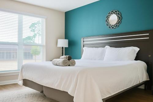 a bedroom with a large white bed with a blue wall at Bliss Living with Pool, Gym & BBQ I Lndry in Houston