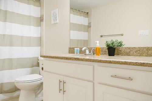 a white bathroom with a toilet and a sink at Bliss Living with Pool, Gym & BBQ I Lndry in Houston