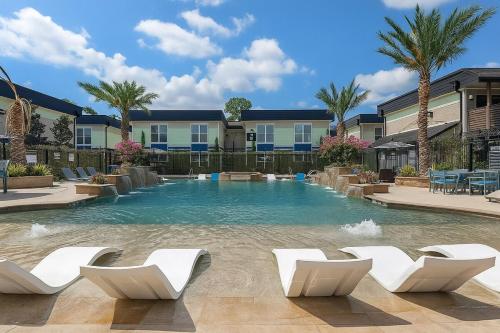 a swimming pool with white chairs and palm trees at Bliss Living with Pool, Gym & BBQ I Lndry in Houston