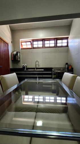 a kitchen with a glass table with chairs and a sink at Apartamento Luxo Centro Paty do Alferes in Paty do Alferes