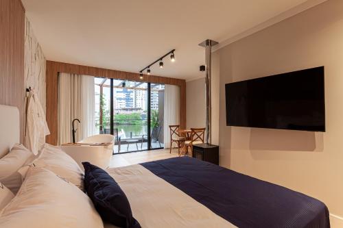 a bedroom with a large bed with a flat screen tv at Azurine Pousada in Passo de Torres