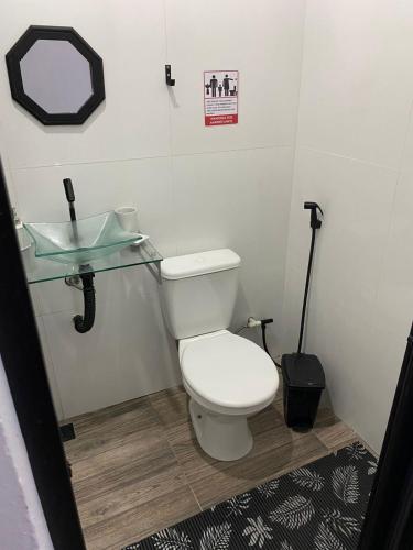 a bathroom with a white toilet and a sink at Hostel Suite Home in Saquarema