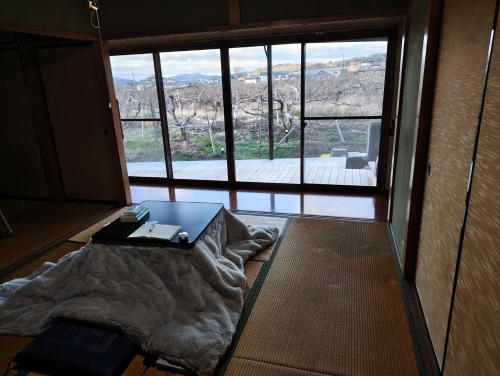 a room with a bed and a table in front of a window at 柿畑の宿 Private stay with farm and house all to yourself in Katsuragi