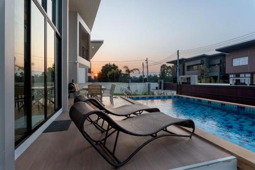 a patio with two chairs next to a swimming pool at Kanna Pool Villa in Chiang Mai