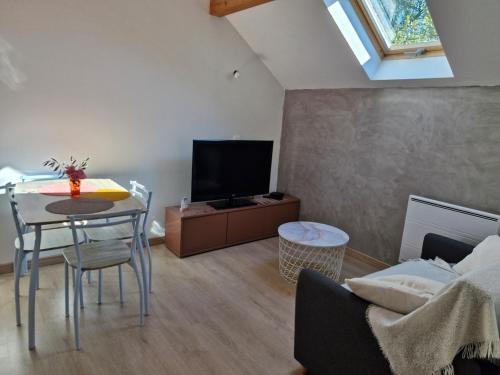 a living room with a table and a tv at Studio indépendant de 2 à 4 personnes in La Biolle