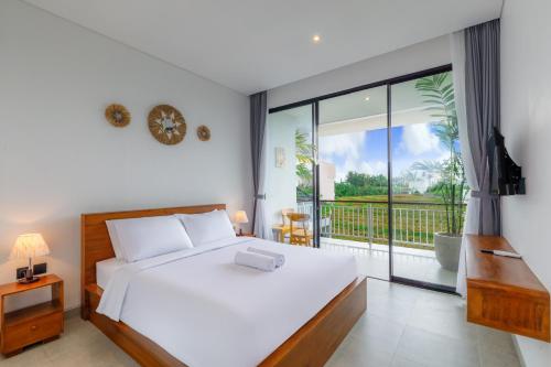 a bedroom with a white bed and a balcony at Famiglie Guest House in Canggu