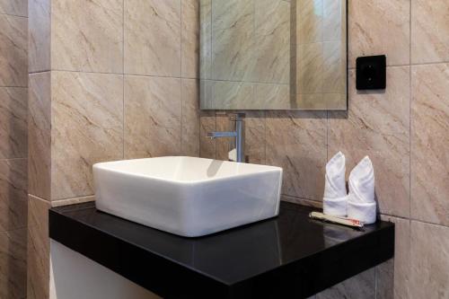 a bathroom with a white sink on a black counter at Famiglie Guest House in Canggu