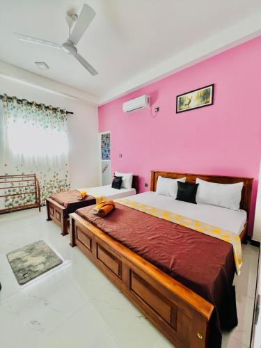 a bedroom with two beds and a pink wall at Messiah Royal Residence in Negombo