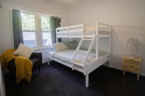 a bedroom with two bunk beds and a chair at Buninyong Golfside Getaway in Buninyong