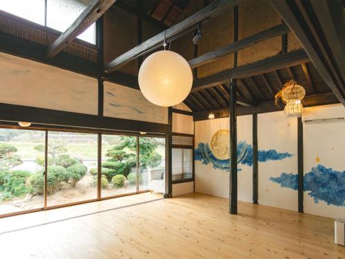 une pièce vide avec de grandes fenêtres et des tableaux aux murs dans l'établissement villa Like hiroshima 愛犬と泊まれる一棟貸し, à Mihara