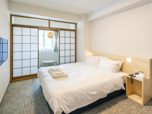a bedroom with a white bed with towels on it at Apartment Hotel DIG the OSAKA in Suita
