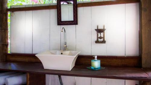 a bathroom with a sink and a mirror and a candle at Maravilla Ojo Del Mar Naturelodge in Puerto Jiménez