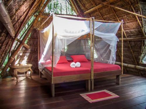 a bedroom with a canopy bed with two white towels at Maravilla Ojo Del Mar Naturelodge in Puerto Jiménez