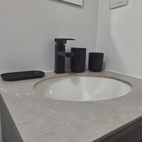a bathroom sink with a faucet and two trash cans at Cabaña Roquin Patagonia in Chile Chico