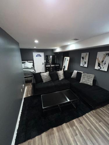 a living room with a black couch and a bed at Comfortstayrus in Orange