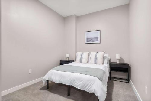 a white bedroom with a bed and two night stands at CozySuites at Textile in Cincinnati