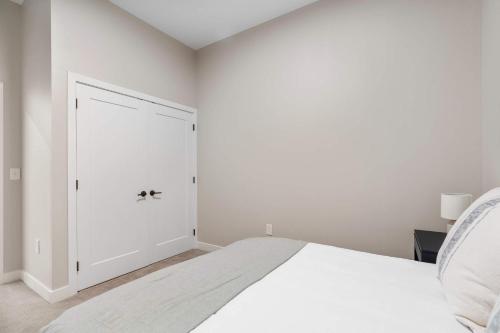 a white bedroom with a bed and a door at CozySuites at Textile in Cincinnati