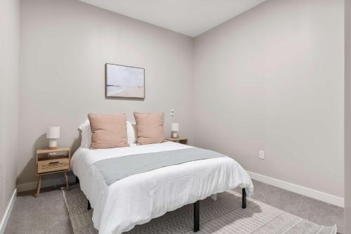 a white bedroom with a bed with two pillows at CozySuites at Textile in Cincinnati
