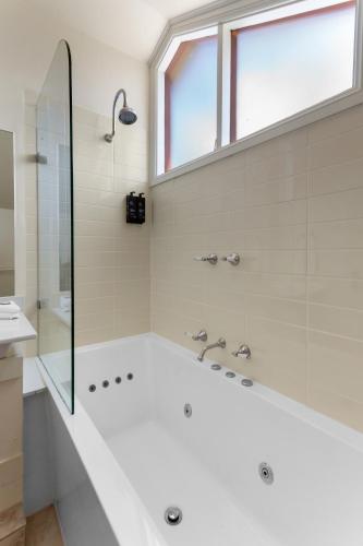 a white bathroom with a shower and a bath tub at La Maison Boutique Hotel in Katoomba
