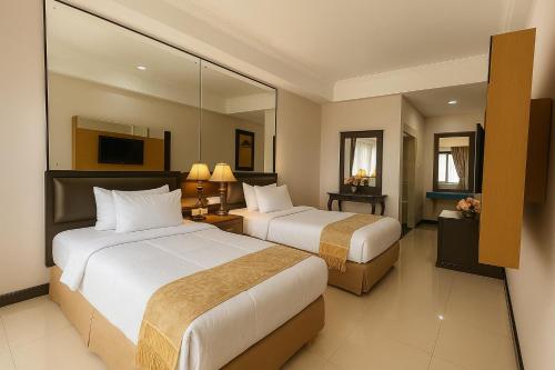 a hotel room with two beds and a mirror at Oak Lawang in Lawang