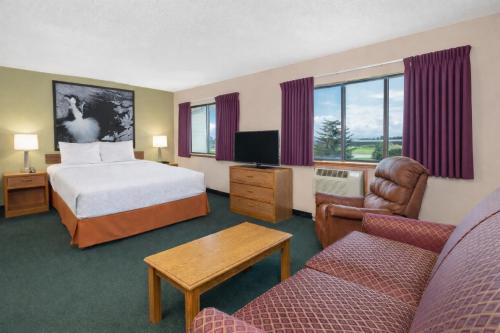 a hotel room with a bed and a tv and a couch at Super 8 by Wyndham Antigo in Antigo