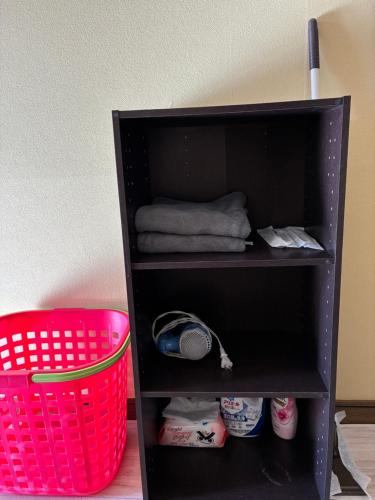 a black book shelf with a basket and towels at アルピエh 108号室WiFi使えます in Hanabatachō