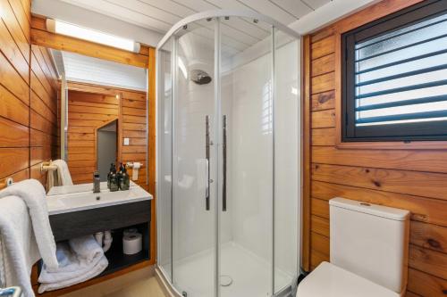 a bathroom with a shower and a toilet and a sink at Smoke Lake Hot Springs Lodge & Camp in Rotorua