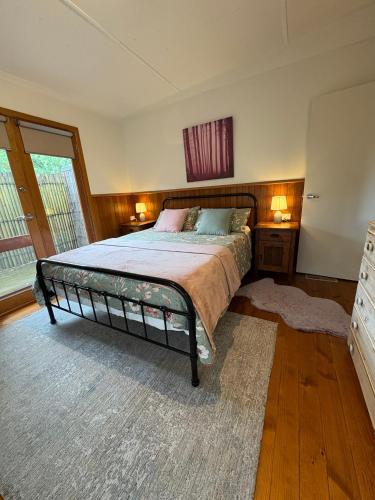 a bedroom with a bed and two night stands and a window at The Green Room Wattle Glen in Wattleglen