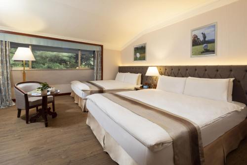 a hotel room with two beds and a table at Taoyuan Yuehua Hotel & Golf Club in Longtan