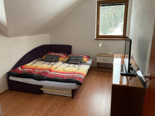 a bedroom with a bed and a table and a window at Apartmán pod kopcom in Telgárt