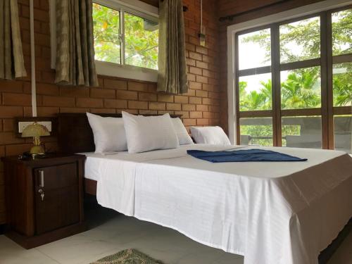 a bedroom with a large white bed with a window at Discovery resort in Ratnapura