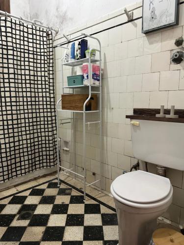 a bathroom with a toilet and a black and white checkered floor at Av corrientes 1 in Buenos Aires