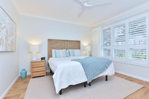 a white bedroom with a bed and a window at Tilligerry Beach Retreat in Taylors Beach