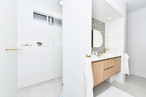 a bathroom with a shower and a sink and a mirror at Tilligerry Beach Retreat in Taylors Beach
