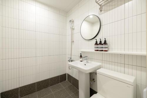 a white tiled bathroom with a sink and a mirror at 미니호텔 먹 in Seoul