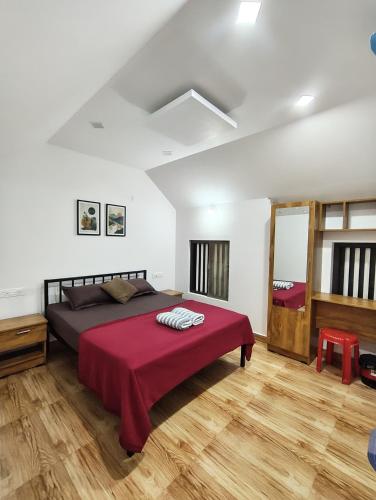 a bedroom with a large bed with a red blanket at Aadhya Homestay 4BHK in Wayanad