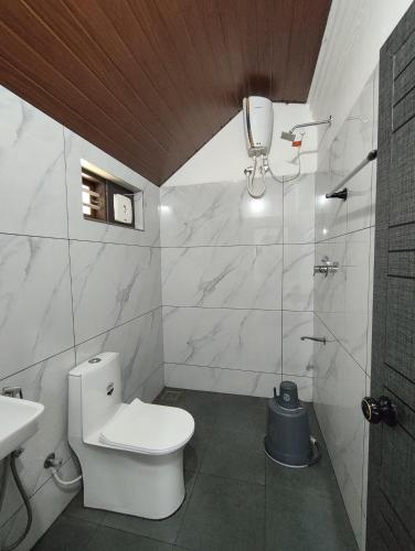 a white bathroom with a toilet and a sink at Aadhya Homestay 4BHK in Wayanad