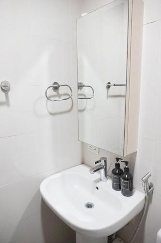 a white bathroom with a sink and a mirror at Eton Baypark Manila Bay in Manila