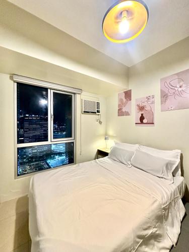 a bedroom with a large white bed and a window at Riala Suite Cebu in Sampong