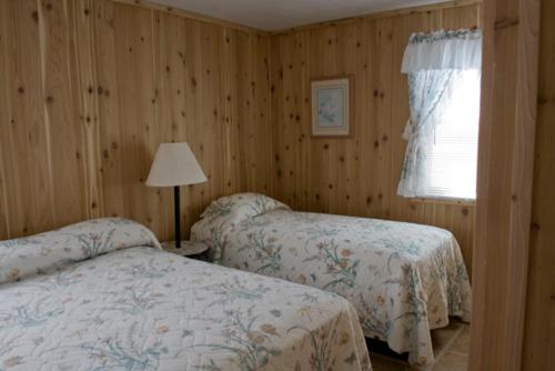 a bedroom with two beds and a lamp and a window at Outer Banks Motel in Buxton