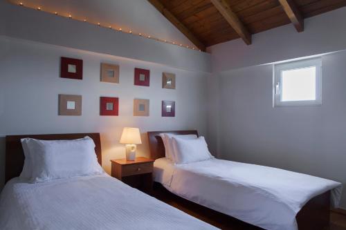 a bedroom with two beds and a table with a lamp at Dialiskari Villas in Marathopolis
