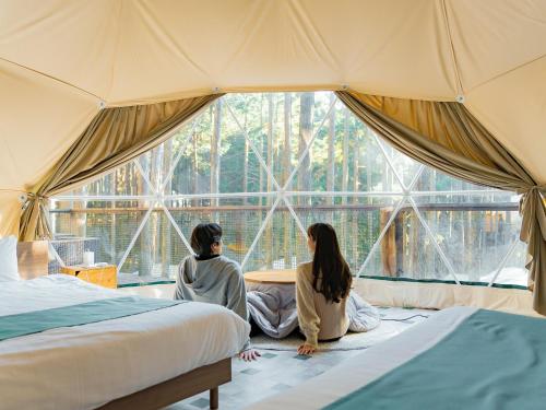 two women sitting in a tent looking out the window at エメラルドの森 in Izunokuni