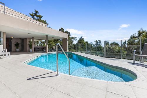 a swimming pool in front of a house at Picture Point Terraces in Noosa Heads