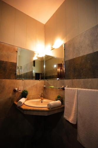 a bathroom with a sink and a mirror and towels at Sardar Villa NathiGalli in Bāzār
