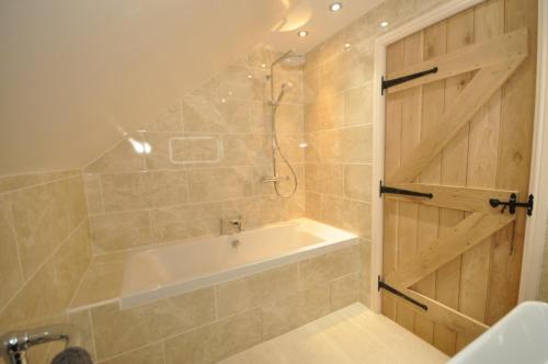 a bathroom with a tub and a wooden door at Montgomery Barn in Bideford