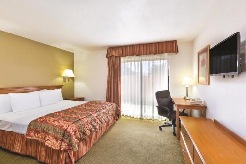 a hotel room with a bed and a desk and a television at Baymont by Wyndham Tehachapi in Tehachapi