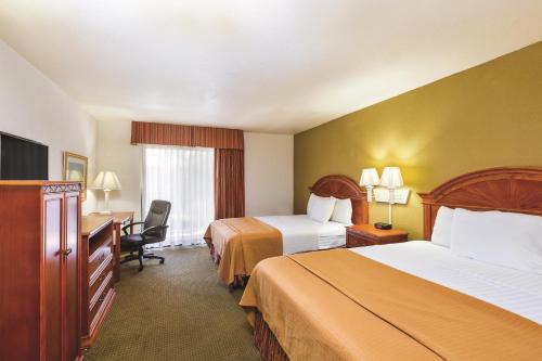 a hotel room with two beds and a desk at Baymont by Wyndham Tehachapi in Tehachapi